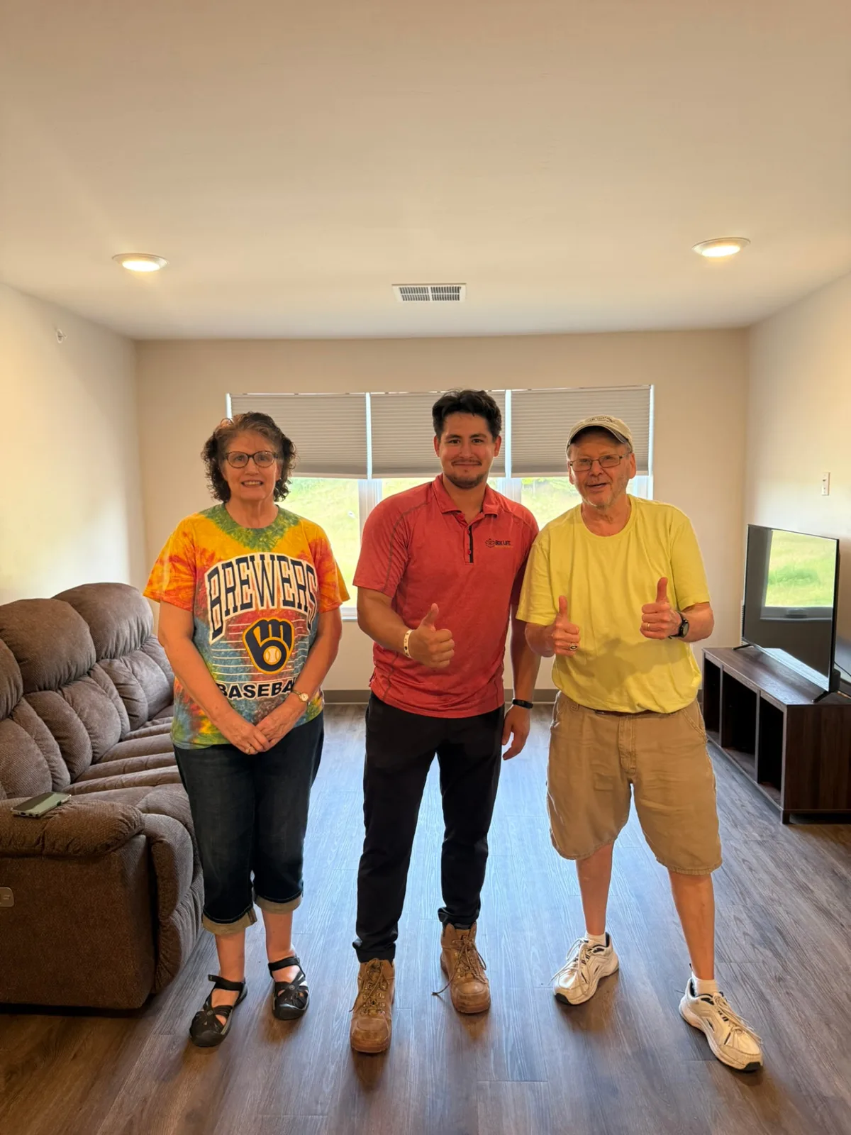 Box Life Moving crew member with happy customers giving thumbs up in their new Madison-area living room