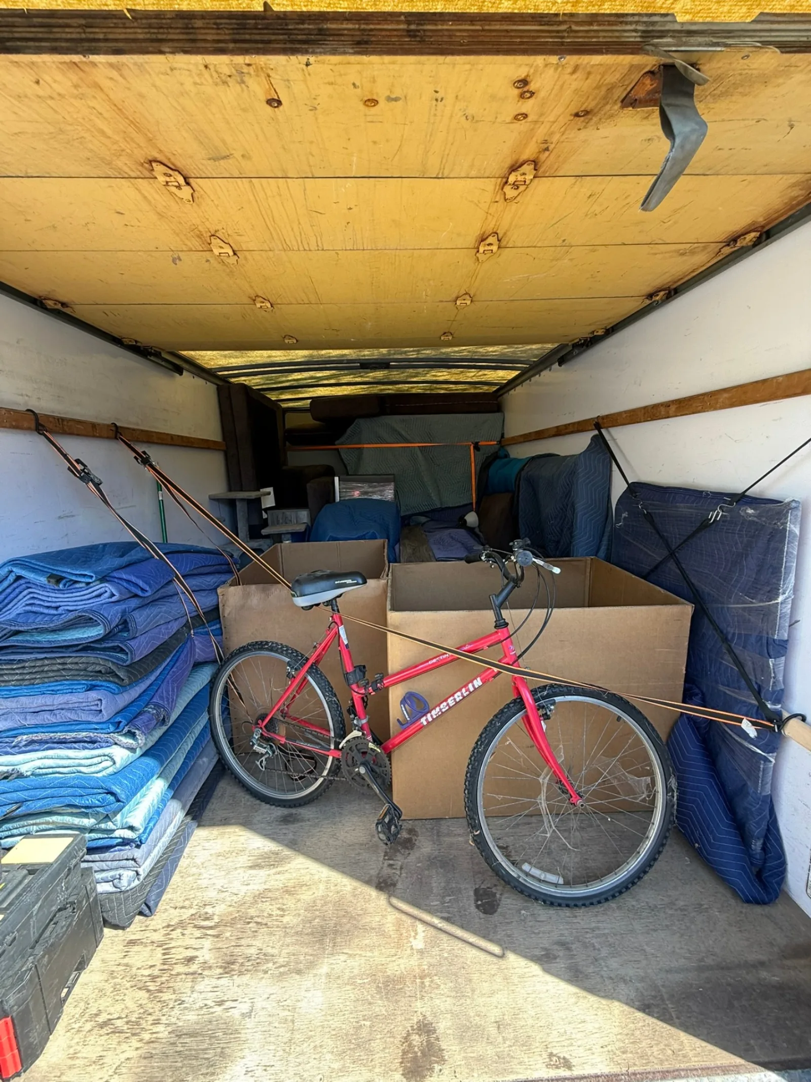 Inside a Box Life Moving truck carefully loaded with a bicycle, boxes, and moving blankets