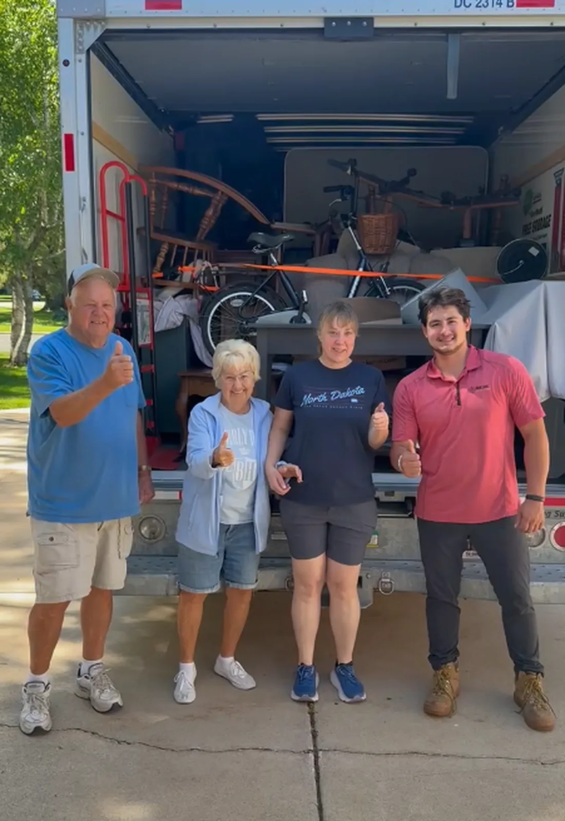 Box Life Moving crew with happy customers giving thumbs up in front of a fully loaded moving truck